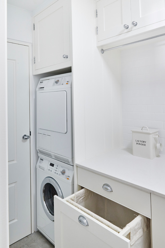 Einzeilige, Mittelgroße Klassische Waschküche mit Unterbauwaschbecken, Schrankfronten im Shaker-Stil, weißen Schränken, weißer Wandfarbe, braunem Holzboden und Waschmaschine und Trockner gestapelt in Sydney