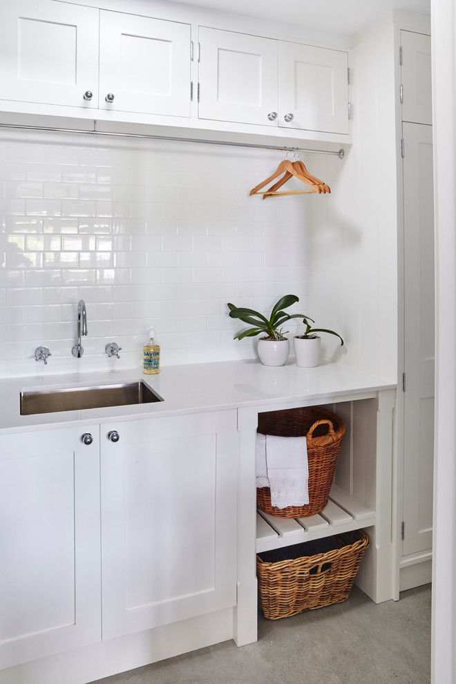 Idéer för mellanstora vintage linjära tvättstugor enbart för tvätt, med en undermonterad diskho, skåp i shakerstil, vita skåp, vita väggar, mellanmörkt trägolv och en tvättpelare