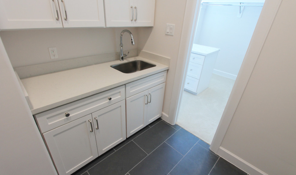 Photo of a classic utility room in Houston with shaker cabinets and white cabinets.