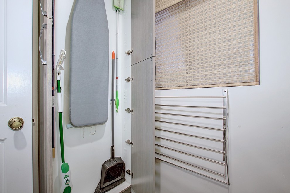 Idee per una lavanderia multiuso minimalista di medie dimensioni con ante lisce, ante grigie, pareti grigie e lavatrice e asciugatrice affiancate
