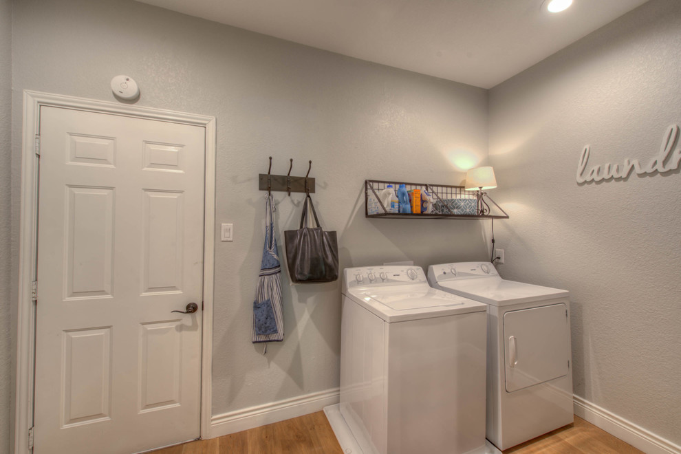 Imagen de cuarto de lavado lineal clásico renovado pequeño con paredes grises, suelo de madera en tonos medios y lavadora y secadora juntas