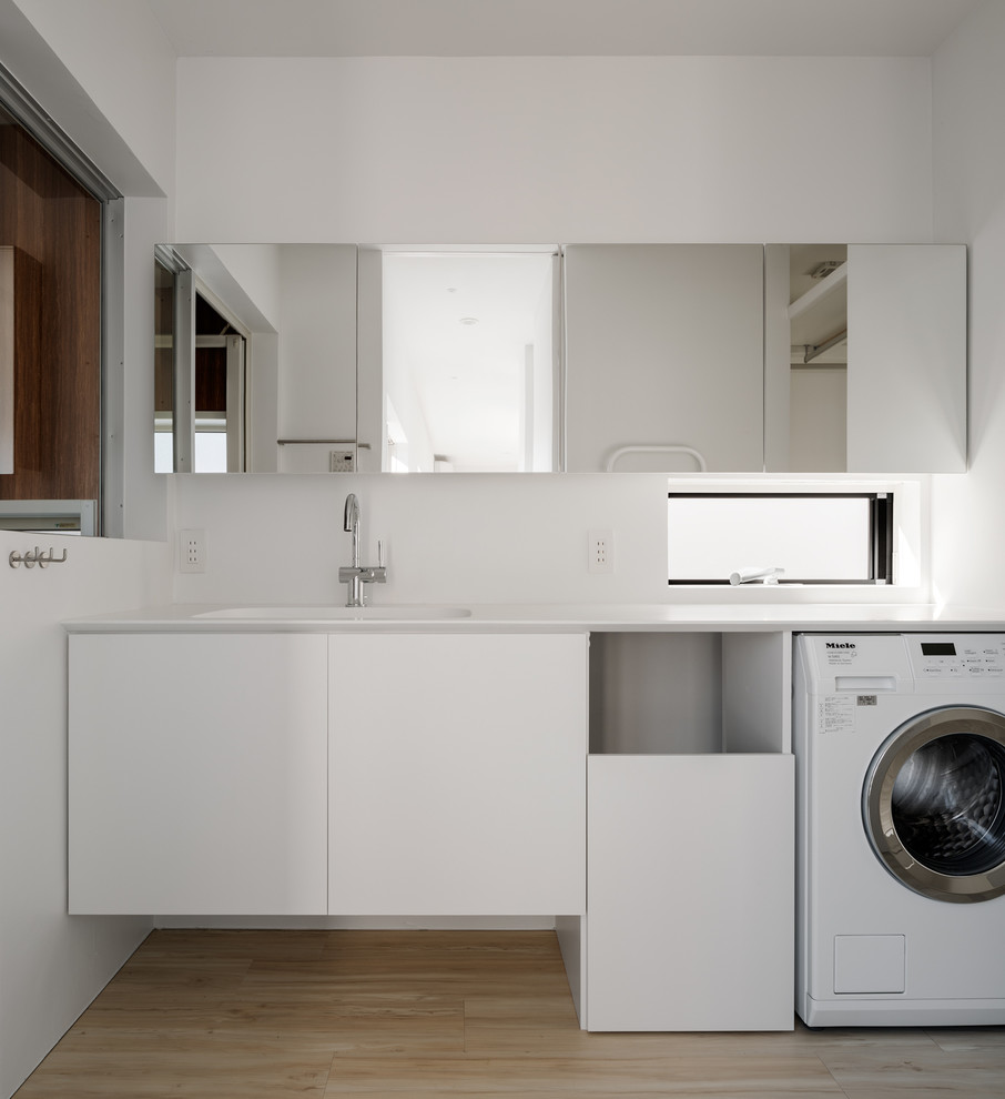 Diseño de lavadero minimalista con fregadero integrado y encimeras blancas