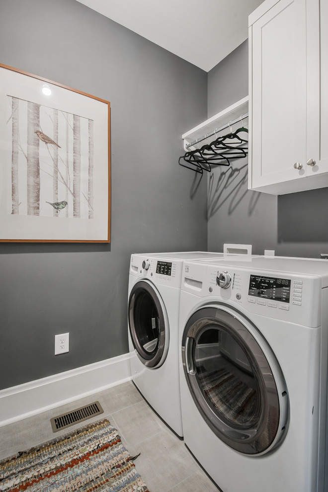 Diseño de lavadero clásico renovado con armarios estilo shaker, puertas de armario blancas, paredes grises y lavadora y secadora juntas