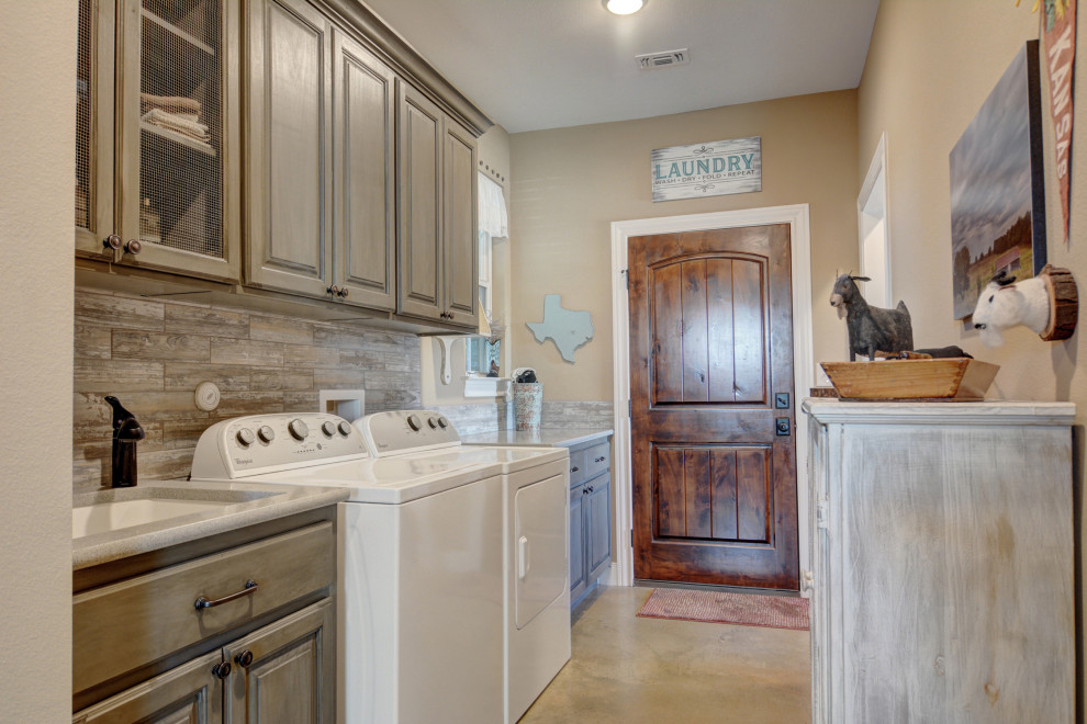 Dedicated laundry room - mid-sized southwestern single-wall concrete floor and beige floor dedicated laundry room idea in Austin with an undermount sink, raised-panel cabinets, gray cabinets, granite countertops, beige walls, a side-by-side washer/dryer and gray countertops