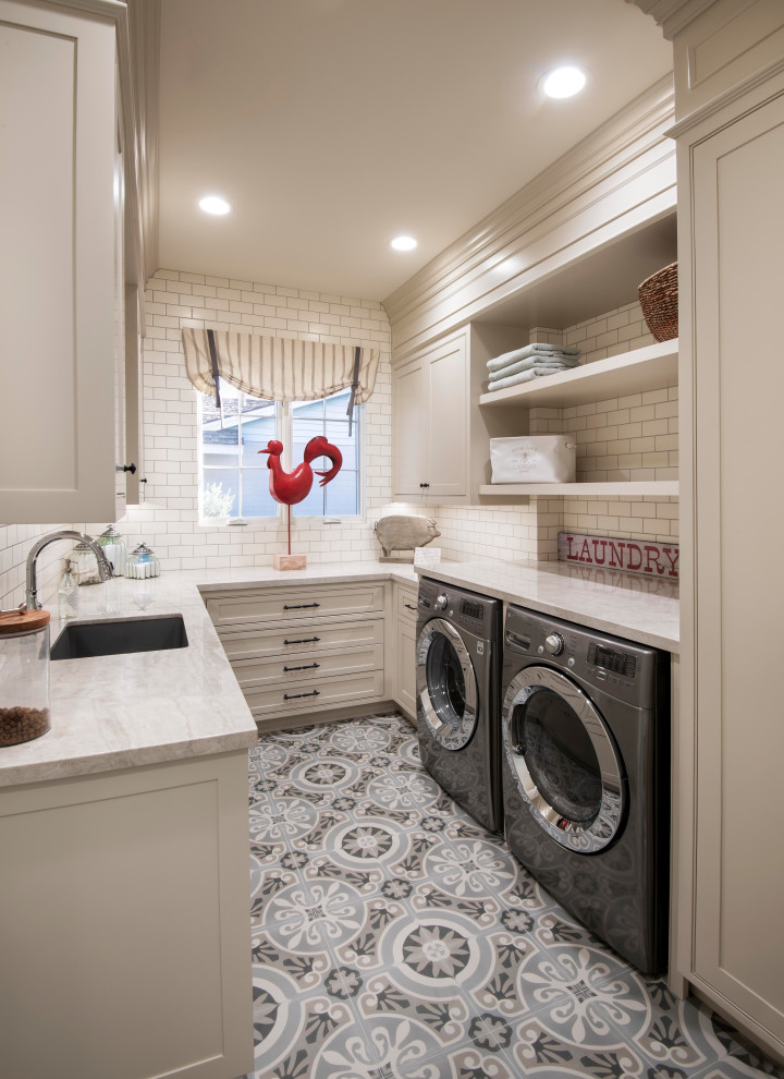 Klassische Waschküche in U-Form mit Unterbauwaschbecken, Kassettenfronten, beigen Schränken, Waschmaschine und Trockner nebeneinander, buntem Boden und beiger Arbeitsplatte in Phoenix