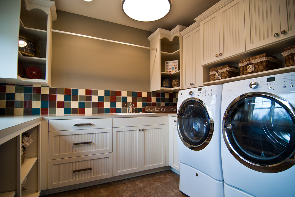 Example of a mid-sized classic u-shaped beige floor dedicated laundry room design in Grand Rapids with a drop-in sink, beaded inset cabinets, white cabinets, laminate countertops, multicolored backsplash, ceramic backsplash, beige walls, a side-by-side washer/dryer and beige countertops