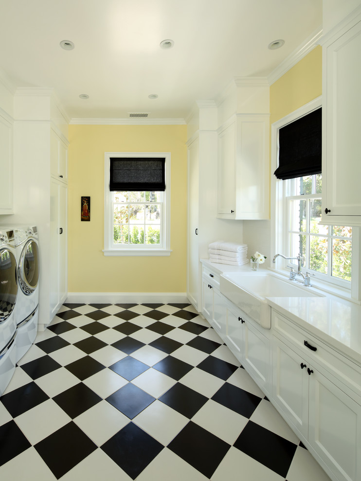 Utility room - huge traditional galley porcelain tile utility room idea in Los Angeles with a farmhouse sink, shaker cabinets, white cabinets, quartzite countertops, yellow walls and a side-by-side washer/dryer