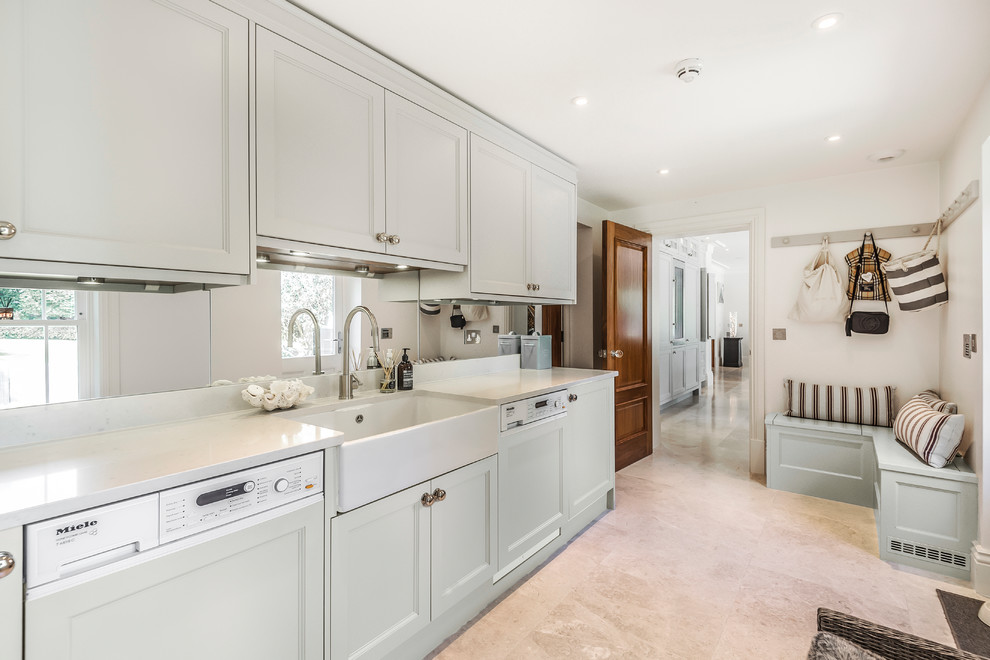 Design ideas for a traditional l-shaped utility room in Berkshire with a belfast sink, recessed-panel cabinets, grey cabinets, white walls, beige floors and white worktops.
