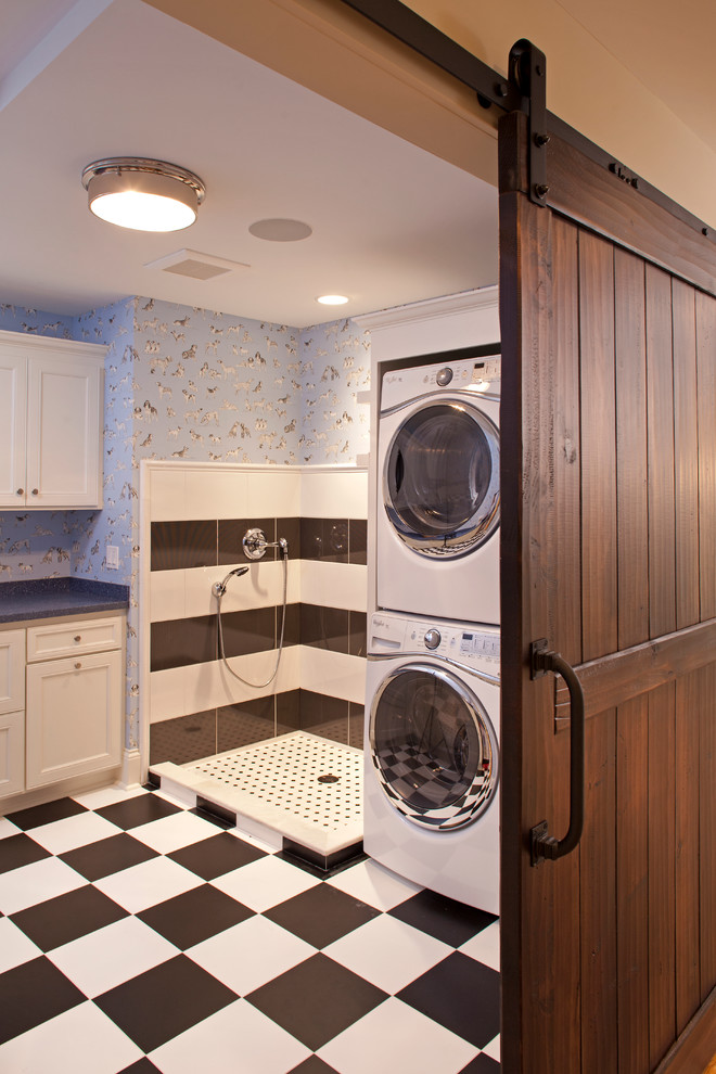 Inredning av en klassisk stor l-formad tvättstuga enbart för tvätt, med luckor med infälld panel, vita skåp, blå väggar, klinkergolv i keramik och en tvättpelare