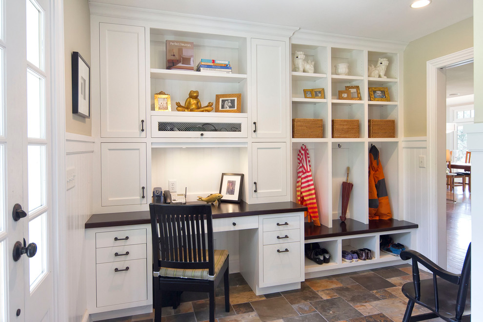 Example of a classic galley slate floor utility room design in New York with flat-panel cabinets, white cabinets, wood countertops, beige walls and black countertops
