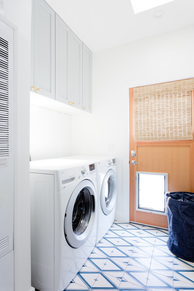 Diseño de cuarto de lavado lineal tradicional renovado con armarios estilo shaker, puertas de armario grises, paredes blancas, lavadora y secadora juntas y suelo multicolor