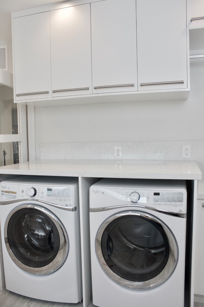 Photo of a large modern galley utility room in Miami with an utility sink, flat-panel cabinets, white cabinets, engineered stone countertops, white walls, marble flooring and a side by side washer and dryer.