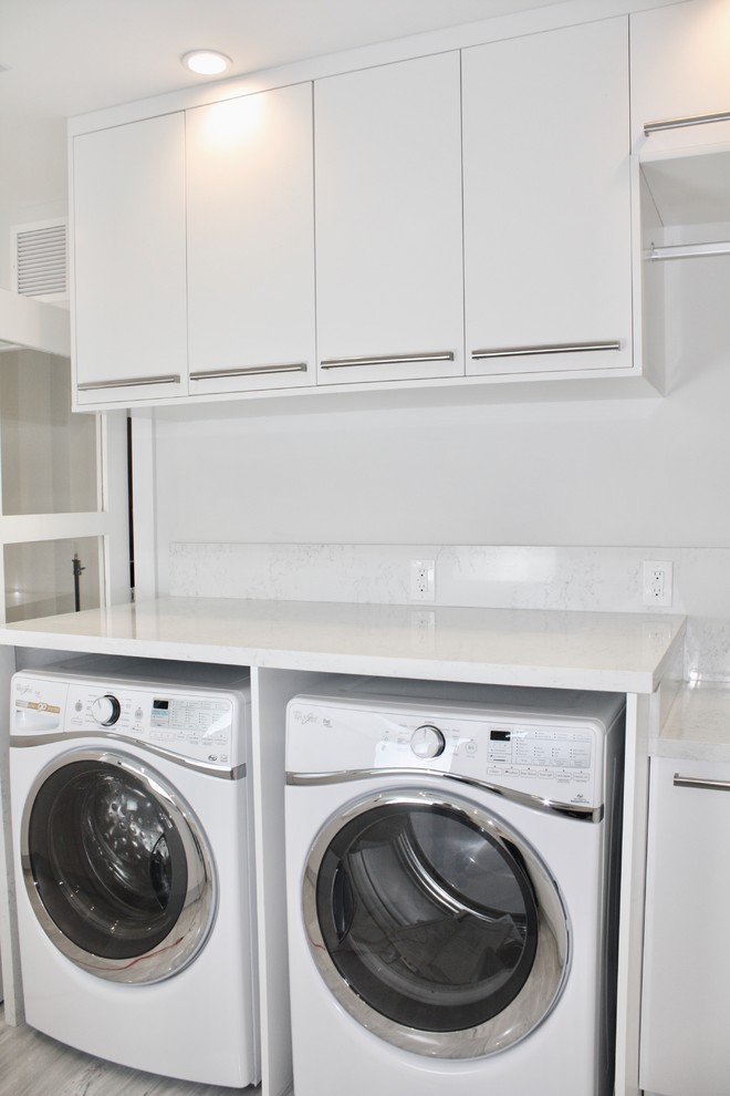 Design ideas for a large modern galley utility room in Miami with flat-panel cabinets, white cabinets, engineered stone countertops, white walls, marble flooring and a side by side washer and dryer.
