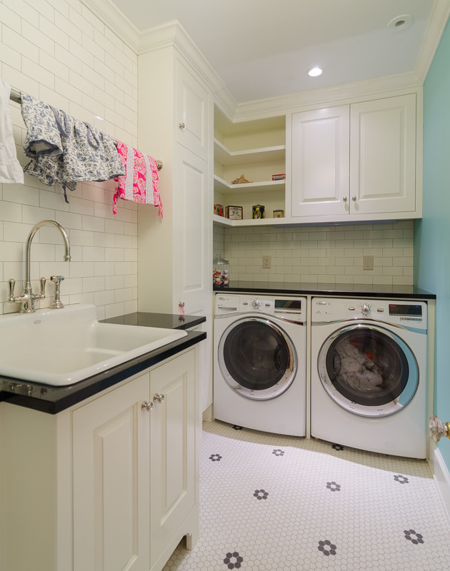 Inredning av en klassisk mellanstor l-formad tvättstuga enbart för tvätt, med en nedsänkt diskho, luckor med upphöjd panel, vita skåp, granitbänkskiva, blå väggar, marmorgolv och en tvättmaskin och torktumlare bredvid varandra