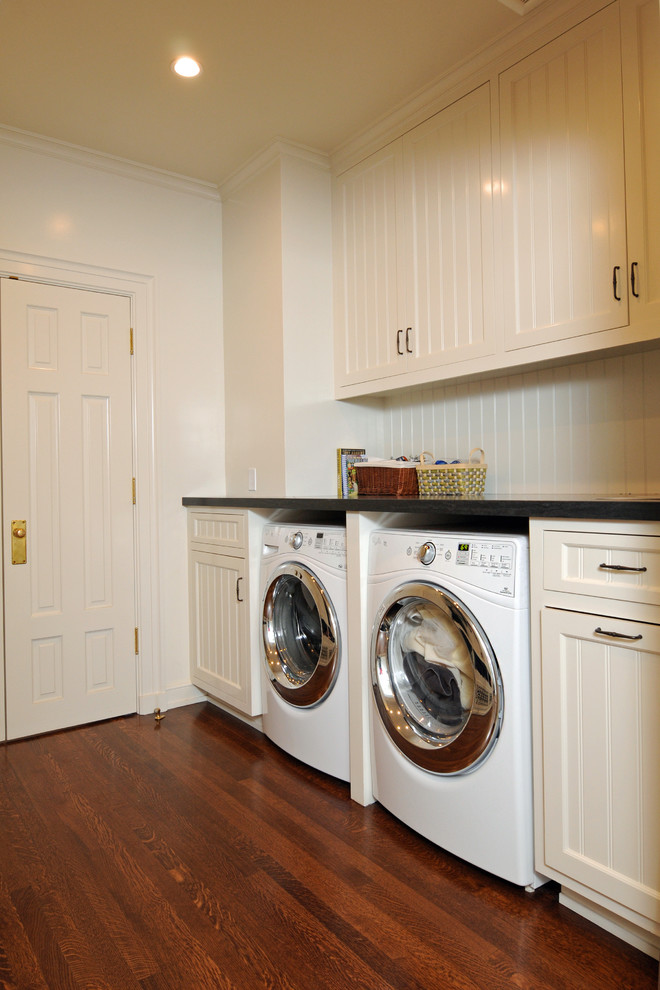Modelo de cuarto de lavado en U tradicional renovado de tamaño medio con puertas de armario blancas, paredes blancas, suelo de baldosas de porcelana, lavadora y secadora juntas y armarios con paneles empotrados