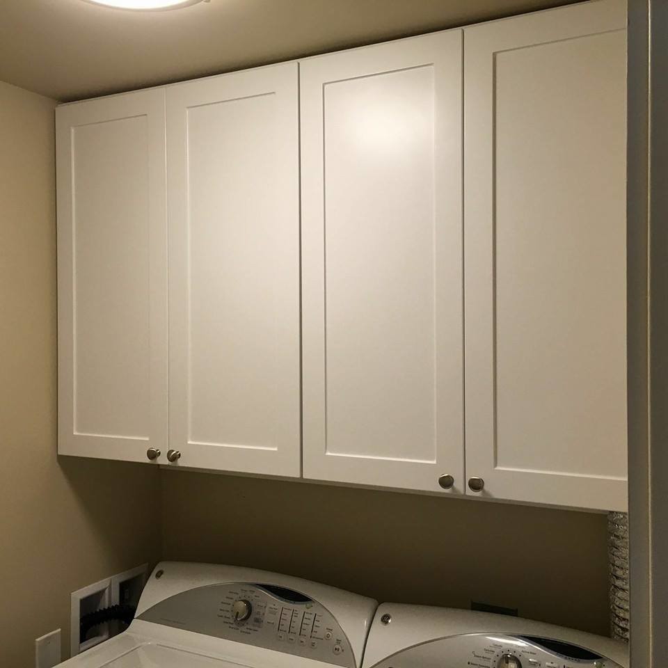 Diseño de cuarto de lavado lineal tradicional grande con armarios estilo shaker, puertas de armario blancas, encimera de acrílico, paredes blancas, suelo de baldosas de cerámica, lavadora y secadora juntas y suelo beige