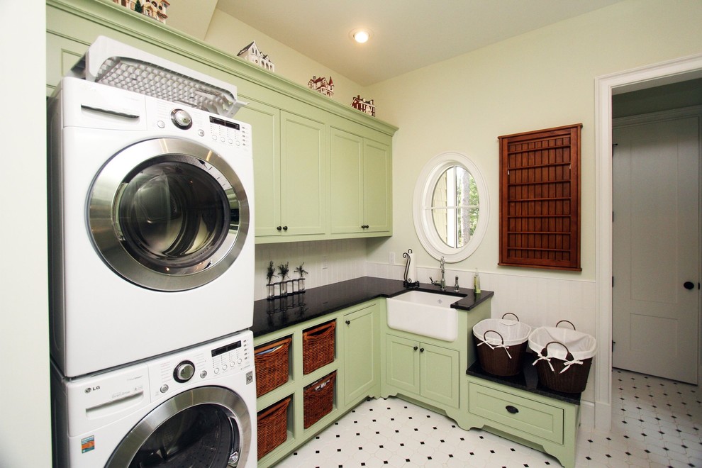Klassischer Hauswirtschaftsraum mit Landhausspüle, grünen Schränken und Waschmaschine und Trockner gestapelt in Jacksonville