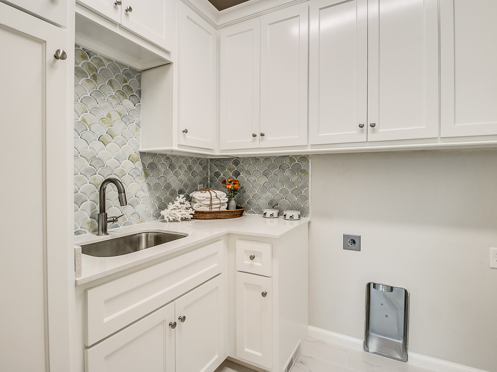 Example of a mid-sized transitional l-shaped ceramic tile and white floor dedicated laundry room design in Oklahoma City with a drop-in sink, shaker cabinets, white cabinets, quartz countertops, gray walls and a side-by-side washer/dryer