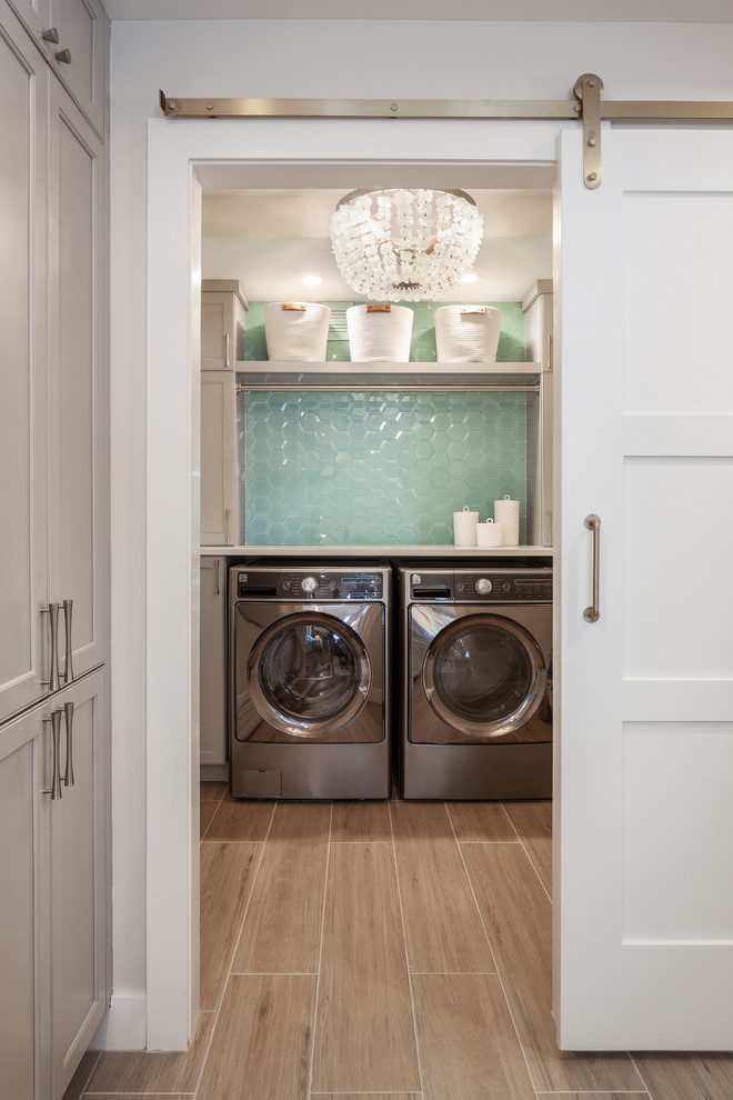 Foto di una piccola sala lavanderia moderna con ante in stile shaker, ante grigie, top in quarzo composito, pareti bianche, pavimento in gres porcellanato, lavatrice e asciugatrice affiancate, pavimento marrone e top bianco