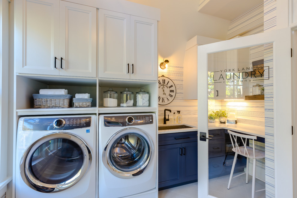 Photo of a large modern l-shaped utility room in Other with a submerged sink, shaker cabinets, blue cabinets, engineered stone countertops, white walls, porcelain flooring, an integrated washer and dryer, white floors and white worktops.