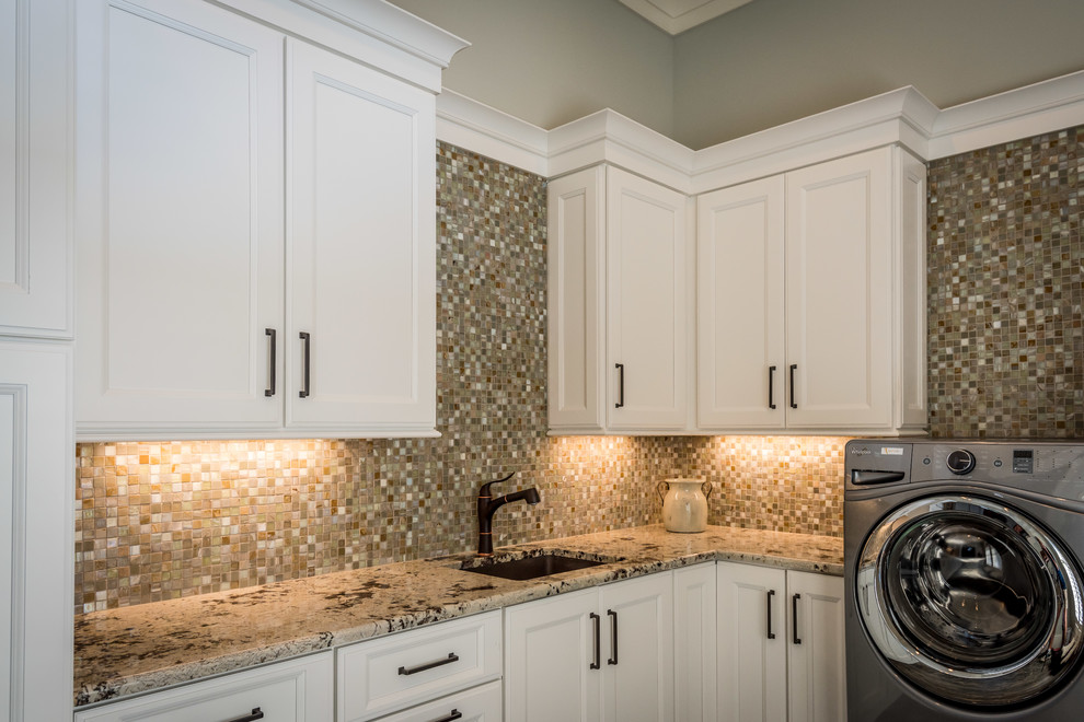 Große Klassische Waschküche in U-Form mit Unterbauwaschbecken, beigen Schränken, Granit-Arbeitsplatte, beiger Wandfarbe, Waschmaschine und Trockner nebeneinander, braunem Boden, Schieferboden und Schrankfronten mit vertiefter Füllung in Charleston