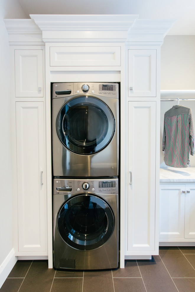 Inredning av en klassisk stor vita u-formad vitt tvättstuga enbart för tvätt, med en rustik diskho, luckor med infälld panel, vita skåp, marmorbänkskiva, beige väggar, tegelgolv, en tvättpelare och svart golv