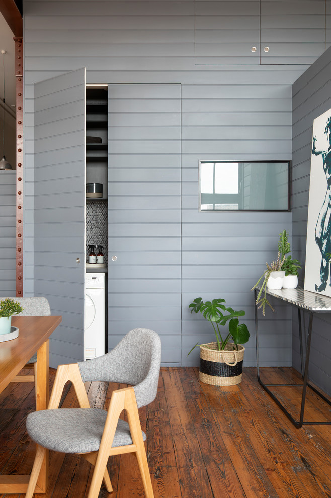 Exempel på en liten modern grå linjär grått tvättstuga enbart för tvätt, med en enkel diskho, släta luckor, grå skåp, bänkskiva i kvarts, grå väggar, mellanmörkt trägolv, tvättmaskin och torktumlare byggt in i ett skåp och brunt golv
