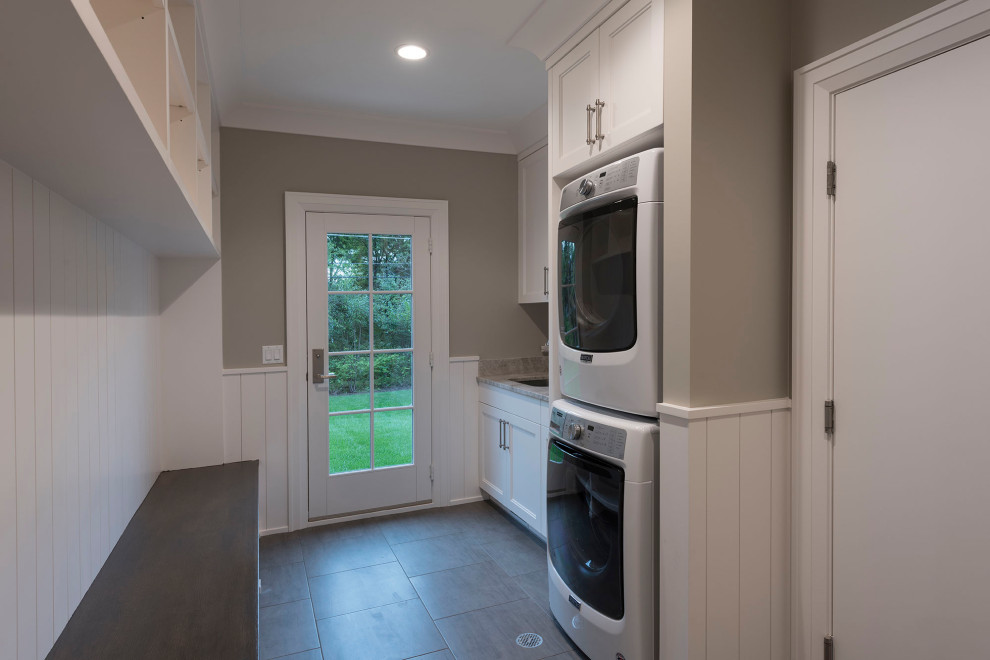 Inspiration for a large classic utility room in Chicago with a built-in sink, shaker cabinets, white cabinets, beige walls, ceramic flooring and a stacked washer and dryer.