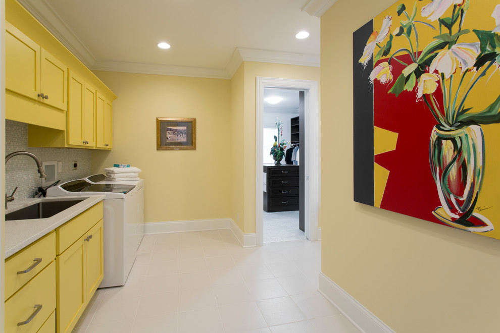 Imagen de lavadero multiusos actual grande con fregadero encastrado, paredes amarillas, suelo de baldosas de cerámica y lavadora y secadora juntas