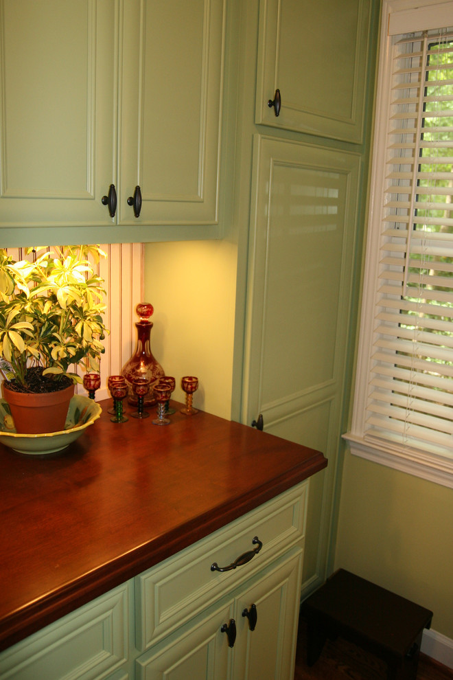 This is an example of a small classic separated utility room in Atlanta with flat-panel cabinets, green cabinets, wood worktops, green walls, medium hardwood flooring and a stacked washer and dryer.