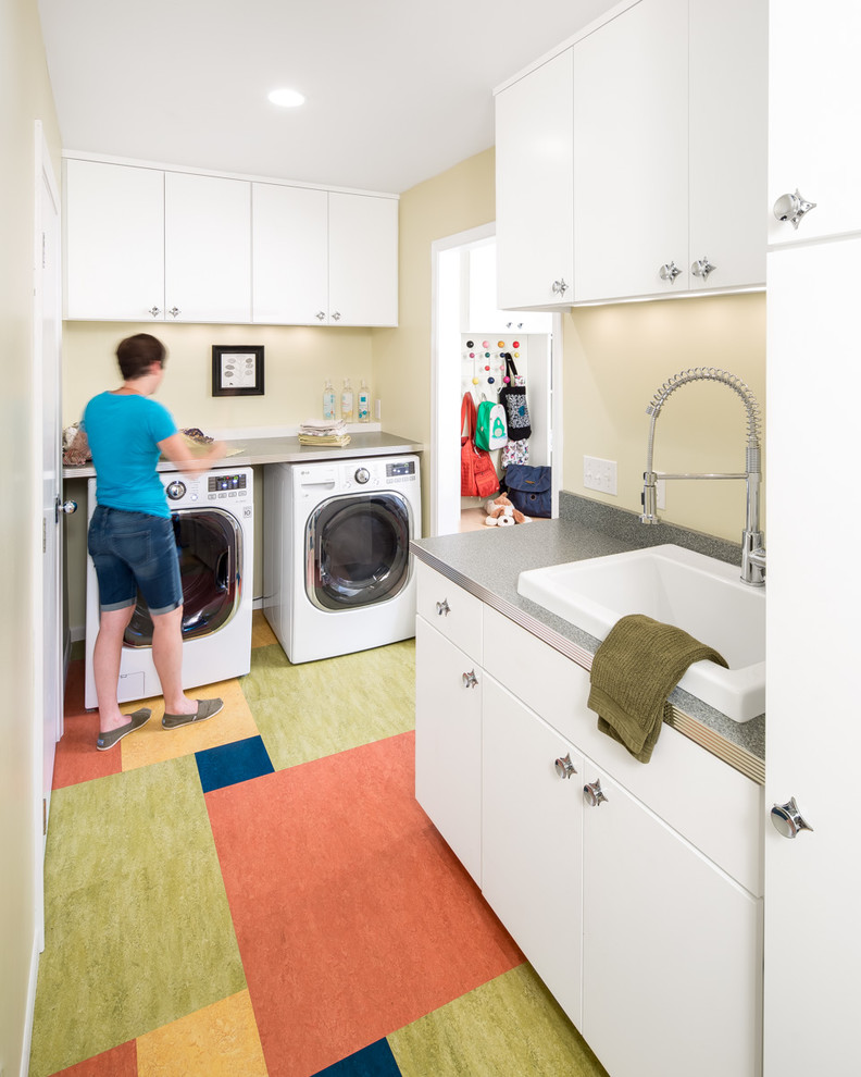 Foto di una sala lavanderia moderna di medie dimensioni con lavello da incasso, ante lisce, ante bianche, pareti beige, lavatrice e asciugatrice affiancate e pavimento multicolore
