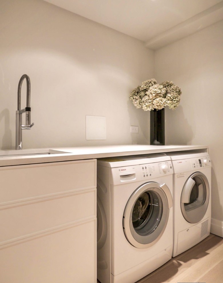 Idee per una sala lavanderia moderna di medie dimensioni con lavello sottopiano, top in quarzo composito, parquet chiaro e lavatrice e asciugatrice affiancate