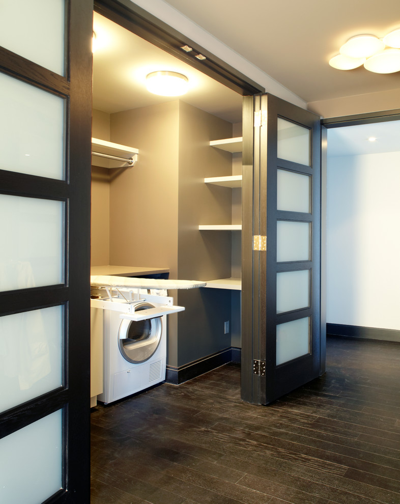 Ejemplo de armario lavadero lineal actual de tamaño medio con armarios abiertos, puertas de armario blancas, encimera de acrílico, paredes beige y suelo de madera oscura