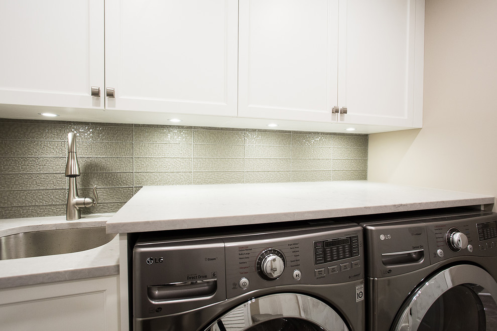 Foto på en mellanstor funkis linjär tvättstuga enbart för tvätt, med en undermonterad diskho, skåp i shakerstil, vita skåp, beige väggar, klinkergolv i keramik, en tvättmaskin och torktumlare bredvid varandra och grått golv