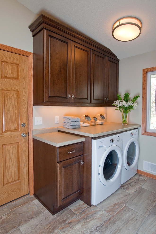 Inspiration for a small classic single-wall utility room in Minneapolis with raised-panel cabinets, dark wood cabinets, laminate countertops, grey walls, porcelain flooring and a side by side washer and dryer.