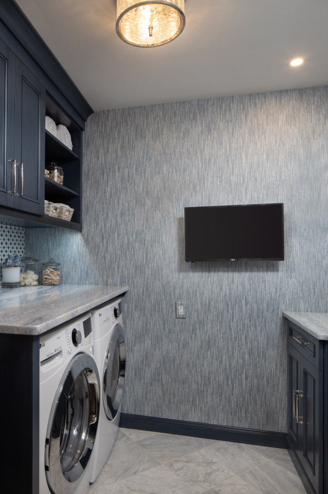 他の地域にある小さなトランジショナルスタイルのおしゃれな洗濯室 (ll型、ドロップインシンク、インセット扉のキャビネット、青いキャビネット、大理石カウンター、マルチカラーのキッチンパネル、磁器タイルのキッチンパネル、青い壁、大理石の床、左右配置の洗濯機・乾燥機、白い床、グレーのキッチンカウンター、壁紙) の写真