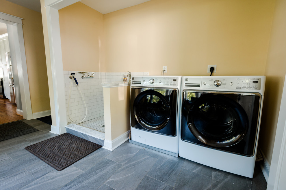 Ejemplo de lavadero multiusos y lineal clásico pequeño con pila para lavar, paredes amarillas, suelo de baldosas de cerámica, lavadora y secadora juntas y suelo gris