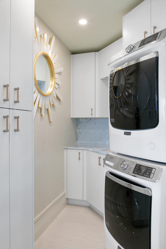 タンパにあるコンテンポラリースタイルのおしゃれなランドリールーム (ll型、フラットパネル扉のキャビネット、白いキャビネット、ベージュの壁、上下配置の洗濯機・乾燥機、ベージュの床、青いキッチンカウンター) の写真