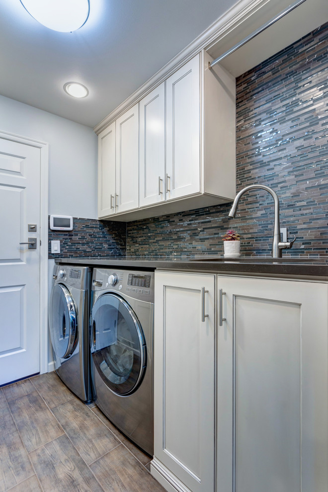 Design ideas for an utility room in Other with a submerged sink, shaker cabinets, white cabinets, engineered stone countertops, white walls, dark hardwood flooring, a side by side washer and dryer, brown floors and black worktops.