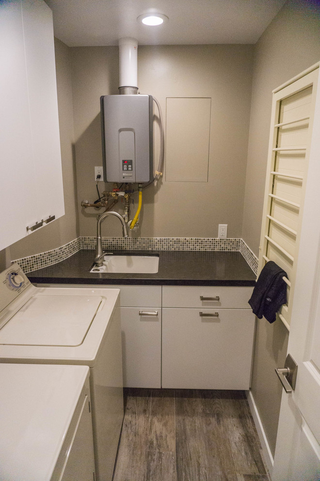 Foto di una piccola sala lavanderia moderna con lavello sottopiano, ante lisce, ante bianche, pareti grigie, pavimento in gres porcellanato e lavatrice e asciugatrice affiancate
