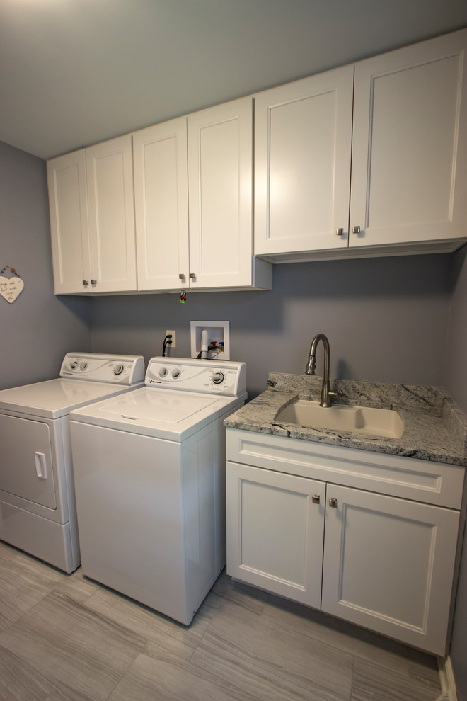 This is an example of a medium sized traditional single-wall separated utility room in Cleveland with an utility sink, recessed-panel cabinets, white cabinets, granite worktops, blue walls, ceramic flooring, a side by side washer and dryer and grey floors.