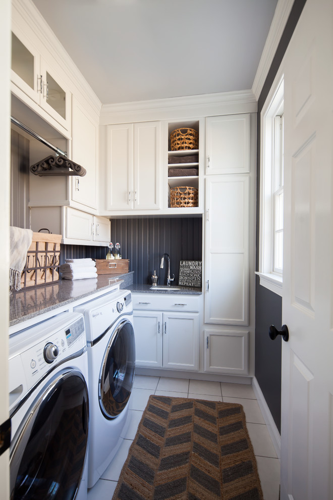 Inspiration för små klassiska l-formade tvättstugor enbart för tvätt, med en undermonterad diskho, luckor med infälld panel, vita skåp, granitbänkskiva, klinkergolv i keramik, en tvättmaskin och torktumlare bredvid varandra och svarta väggar