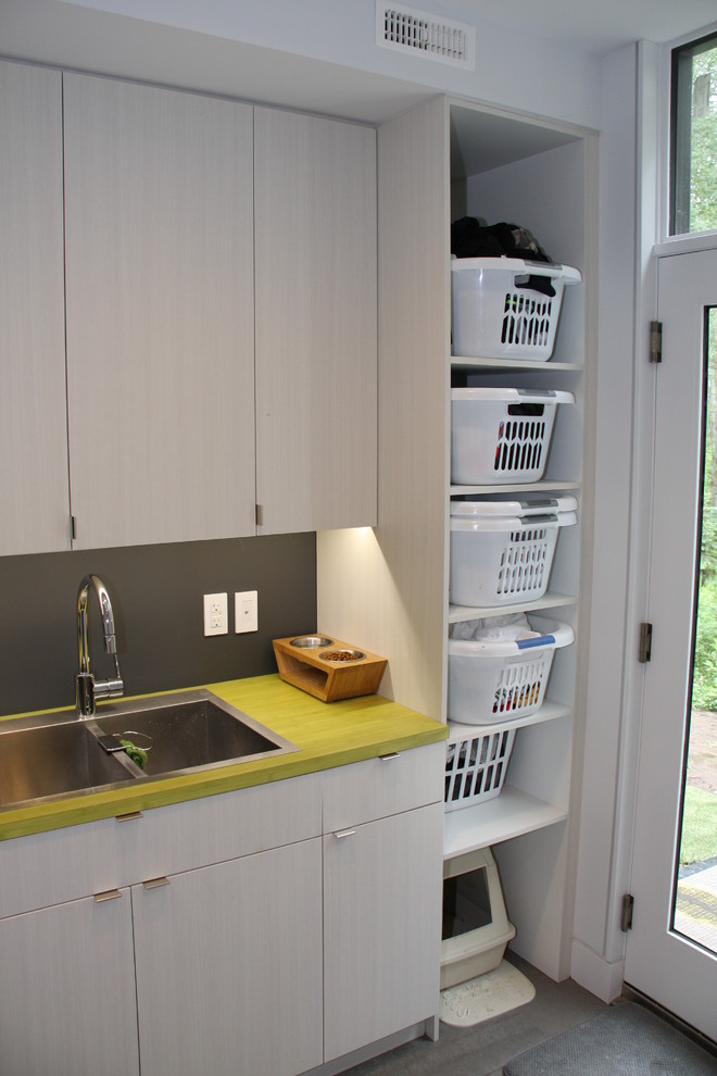 Idéer för mellanstora funkis gult tvättstugor enbart för tvätt, med en dubbel diskho, släta luckor, grå skåp, laminatbänkskiva, grå väggar, mellanmörkt trägolv, en tvättmaskin och torktumlare bredvid varandra och grått golv