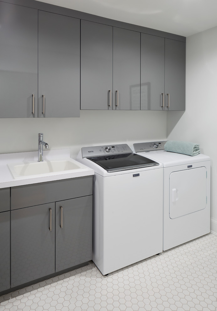 Design ideas for a large contemporary single-wall separated utility room in Grand Rapids with a built-in sink, flat-panel cabinets, grey cabinets, engineered stone countertops, grey walls, ceramic flooring, a side by side washer and dryer, white floors and white worktops.