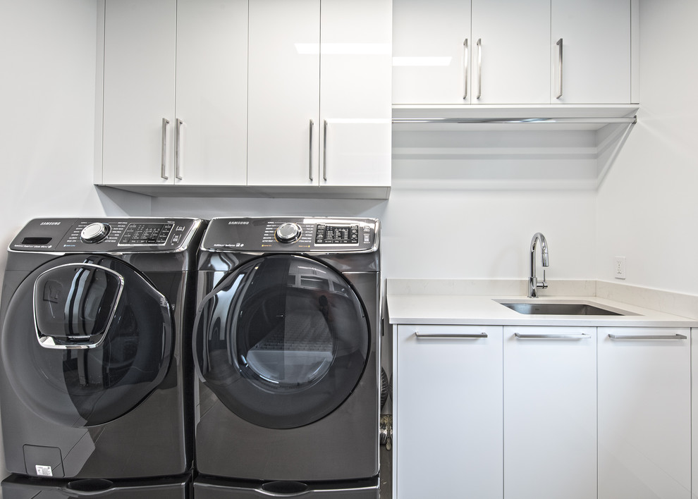 シアトルにある高級な中くらいなコンテンポラリースタイルのおしゃれな洗濯室 (アンダーカウンターシンク、フラットパネル扉のキャビネット、白いキャビネット、人工大理石カウンター、白い壁、左右配置の洗濯機・乾燥機) の写真