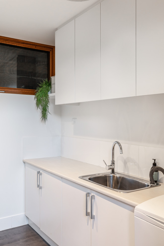 Idéer för en mellanstor modern grå parallell tvättstuga, med en enkel diskho, vita skåp, laminatbänkskiva och vita väggar