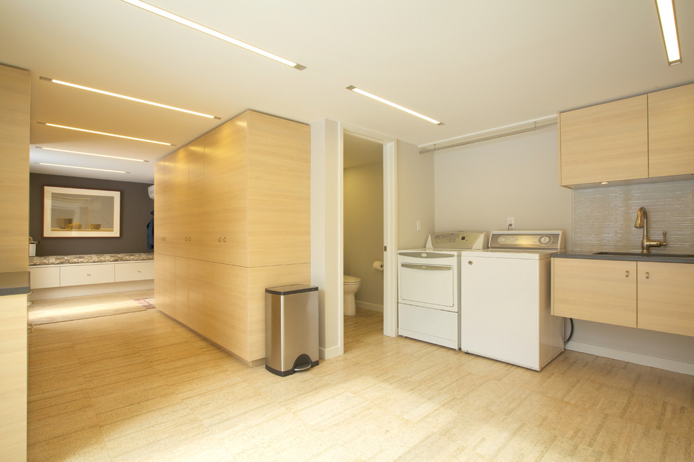 Expansive contemporary l-shaped utility room in Philadelphia with a submerged sink, flat-panel cabinets, light wood cabinets, beige walls, bamboo flooring and a side by side washer and dryer.