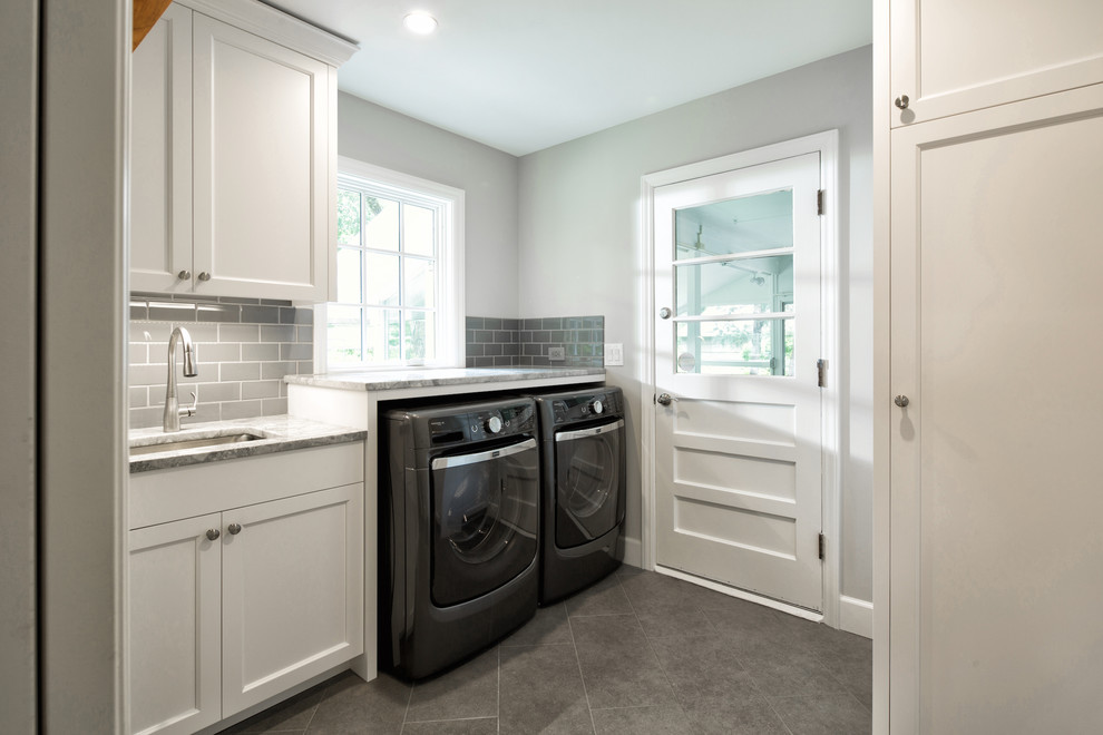 Immagine di una sala lavanderia minimal di medie dimensioni con lavello sottopiano, ante in stile shaker, ante bianche, top in granito, pareti grigie, pavimento in gres porcellanato e lavatrice e asciugatrice affiancate