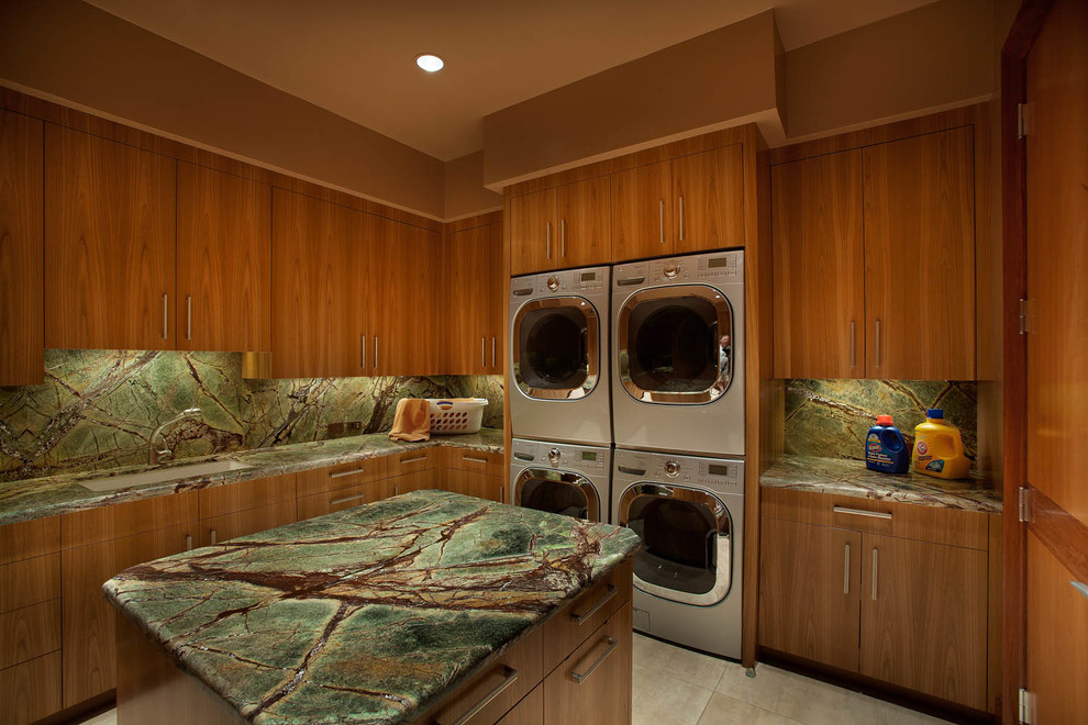 Foto på en stor funkis u-formad tvättstuga, med en undermonterad diskho, släta luckor, skåp i mellenmörkt trä, bruna väggar, en tvättpelare och beiget golv