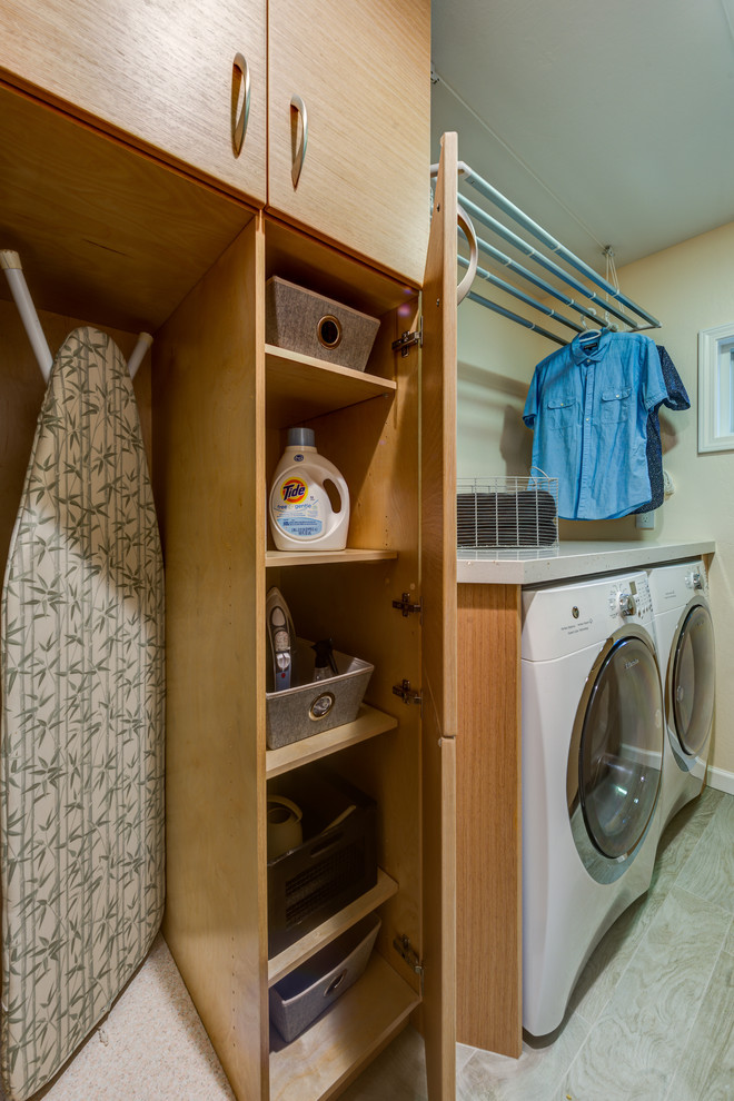 Foto di una sala lavanderia minimal di medie dimensioni con ante lisce, top in quarzo composito, ante in legno chiaro e pavimento in laminato